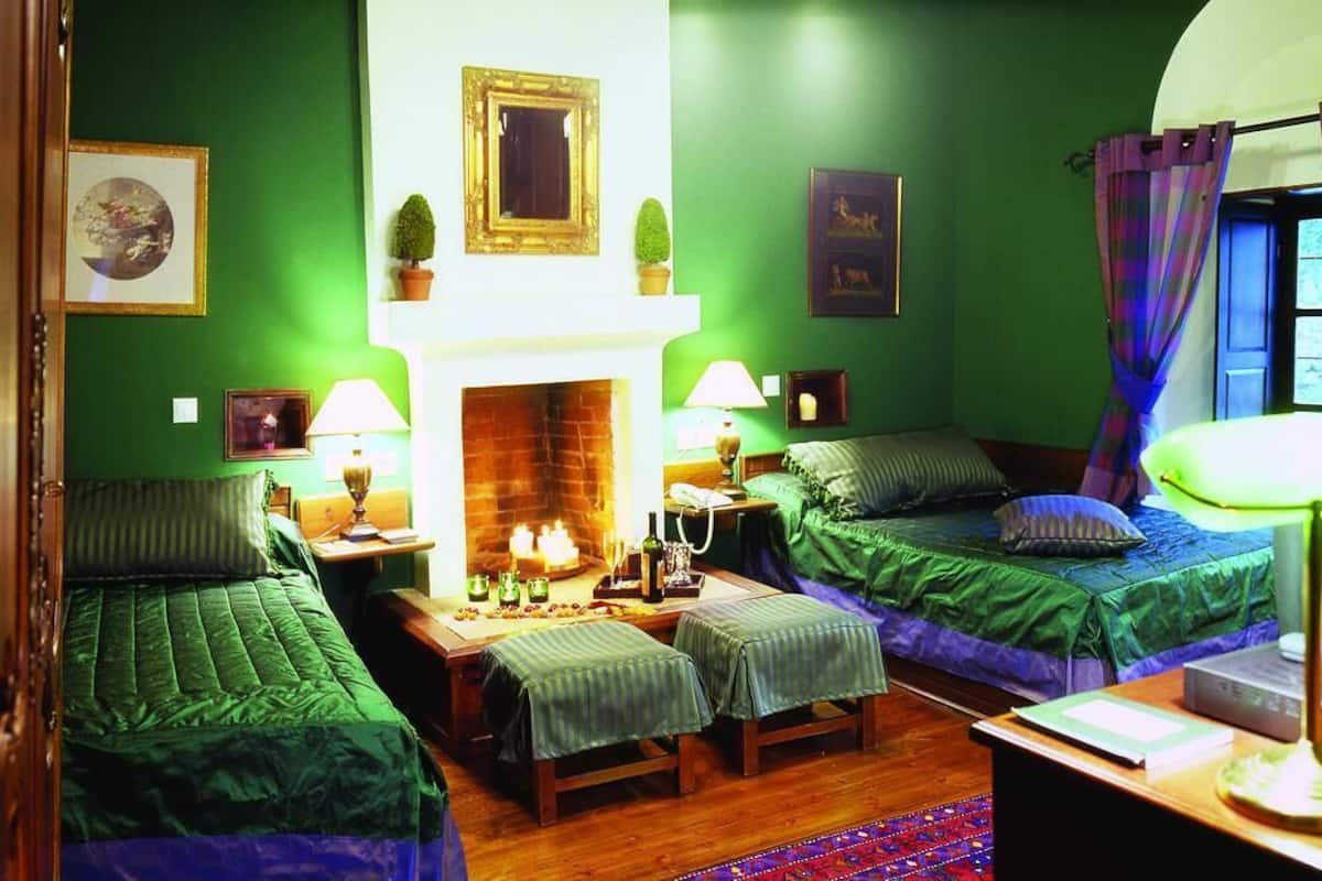 A room with two single beds, a fireplace, and a small table with a lamp.