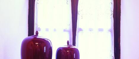 Una ventana con dos jarrones rojos en el alféizar.