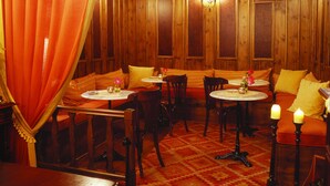 A cozy restaurant with wooden paneling, round tables, and benches. - Santikos Mansion (South Pelion)