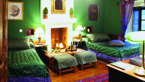 A room with two beds, a fireplace, and green walls. - Santikos Mansion (South Pelion)