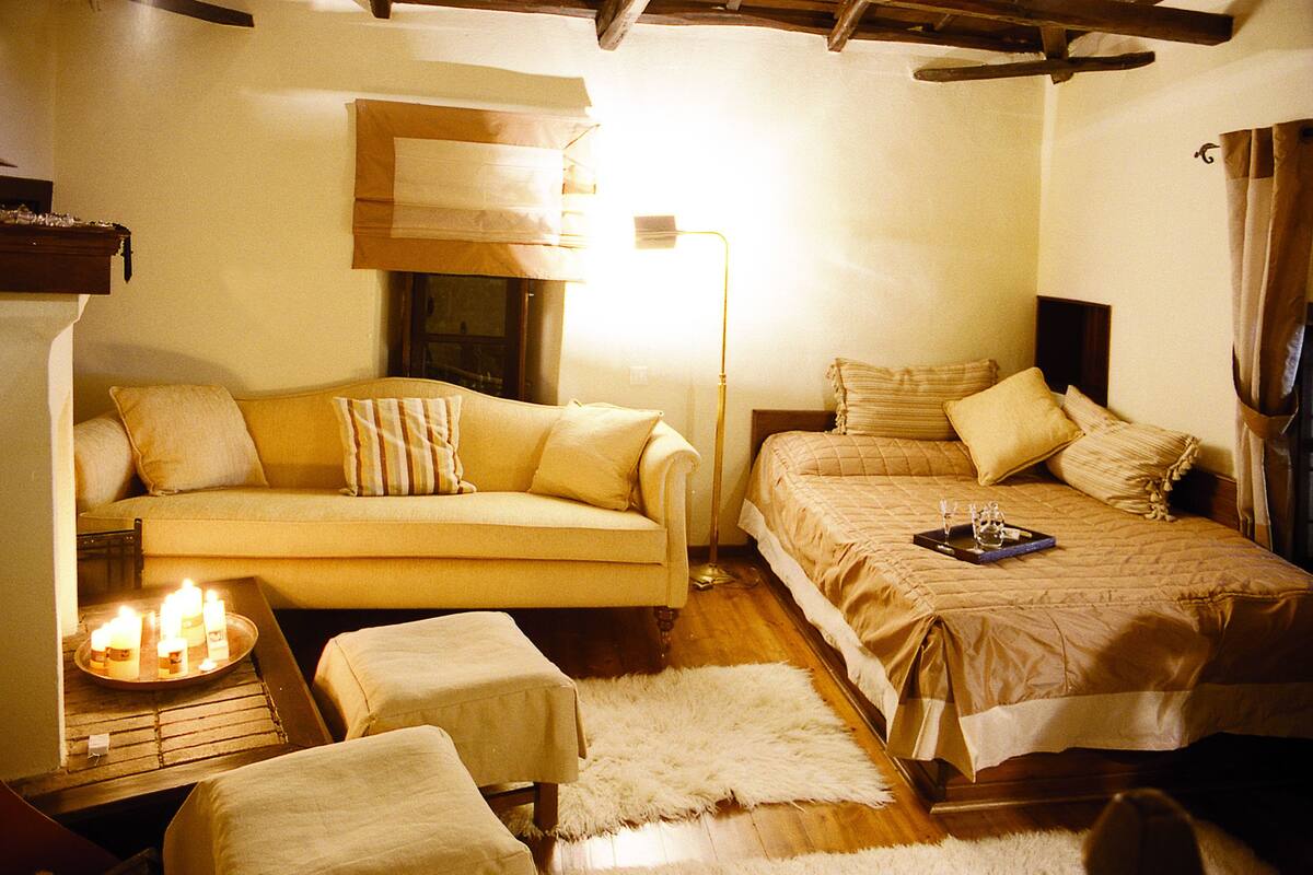 A cozy room with a sofa, a bed, a small table with candles, and a lamp.