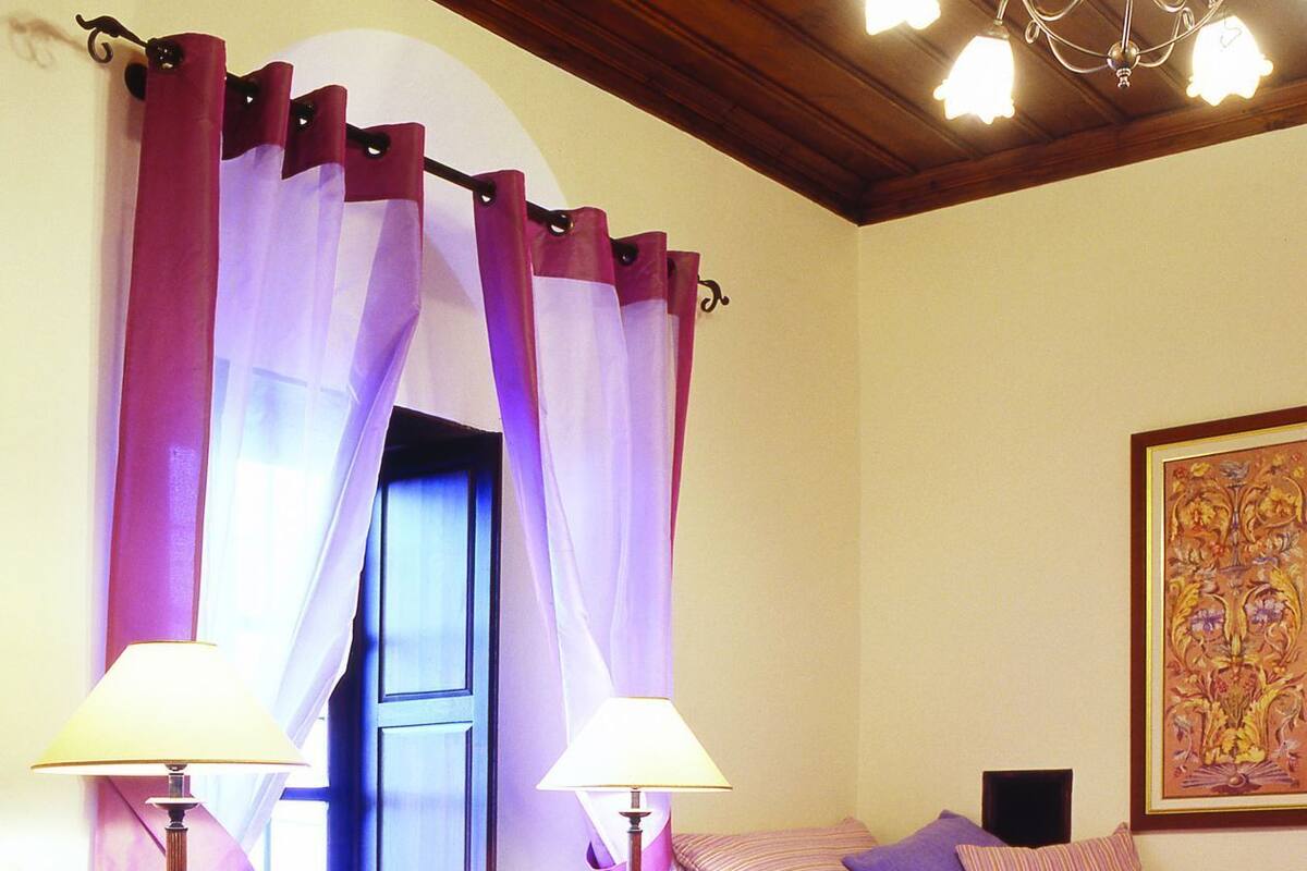 A bedroom with two beds, a chandelier, a decorative painting, and a tray with a teapot and cup.