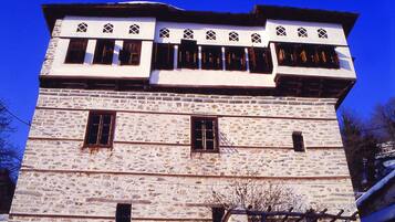 A multi-story stone building with a flat roof and multiple windows.