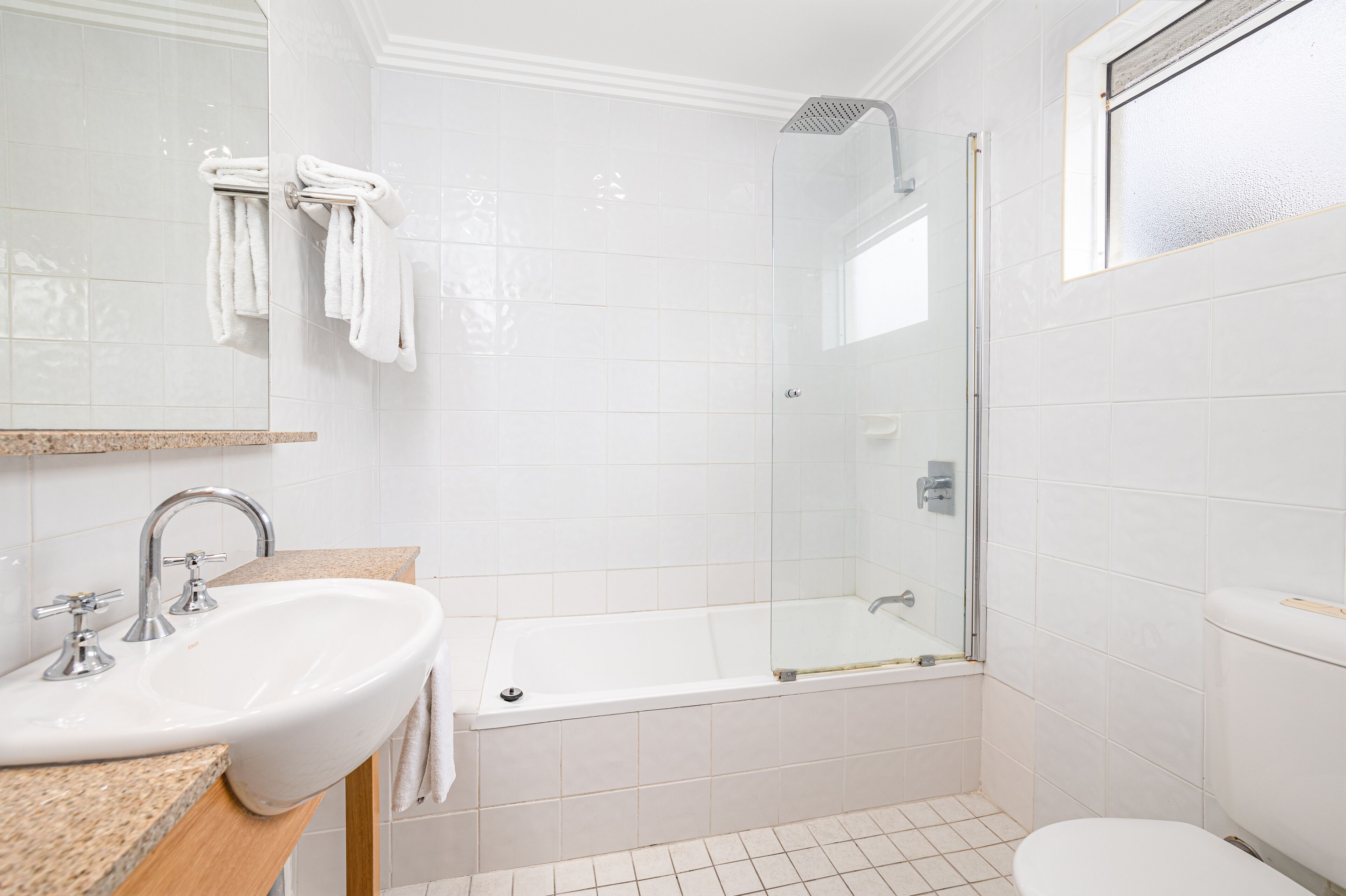 Une salle de bain équipée d’un lavabo, d’un miroir et d’une douche à parois de verre.