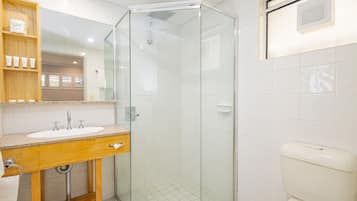 Une salle de bain avec une douche à parois de verre, un meuble-lavabo en bois et des toilettes.