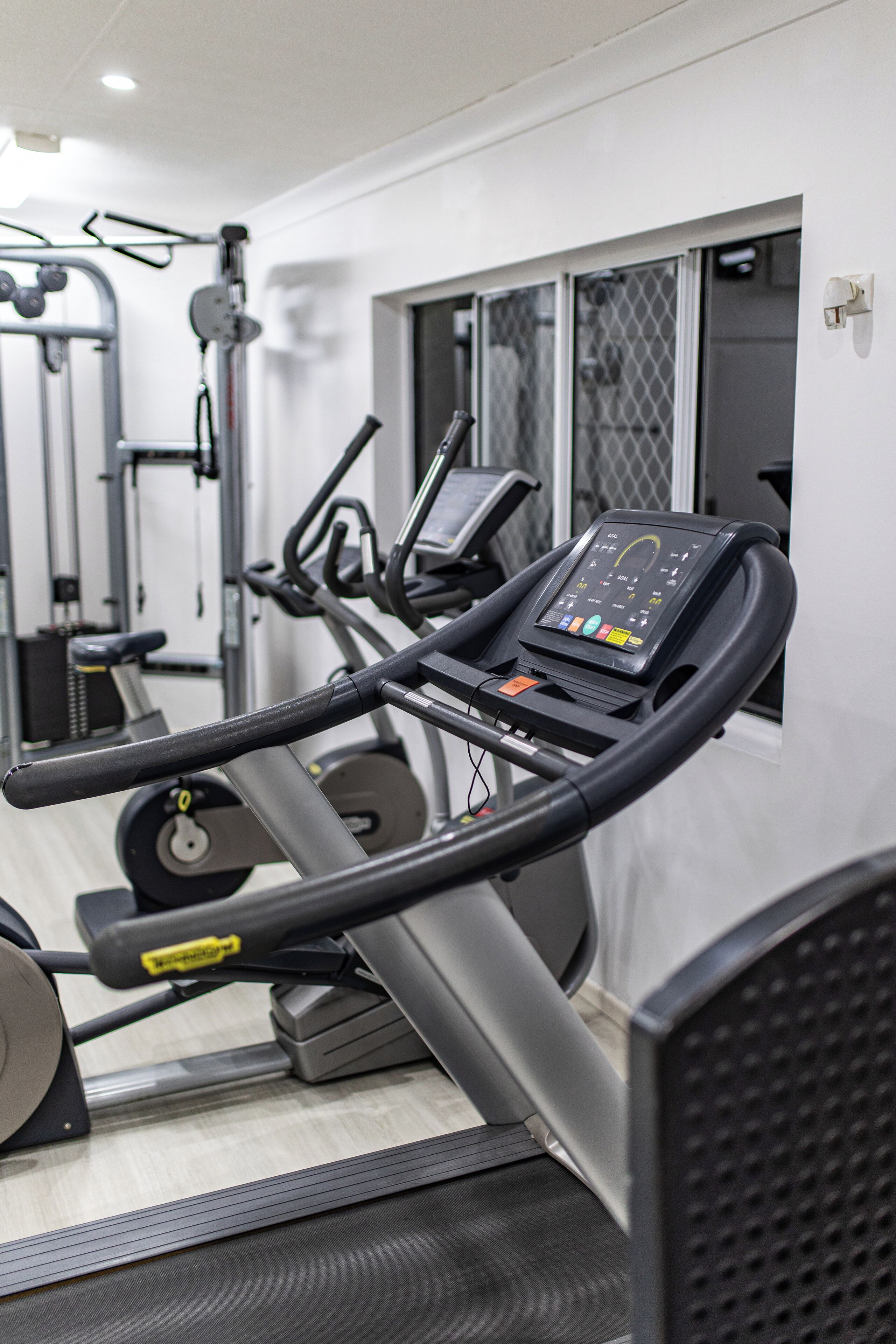 Une salle de sport équipée de tapis de course, d’appareils d’exercice et d’un panneau de commande.