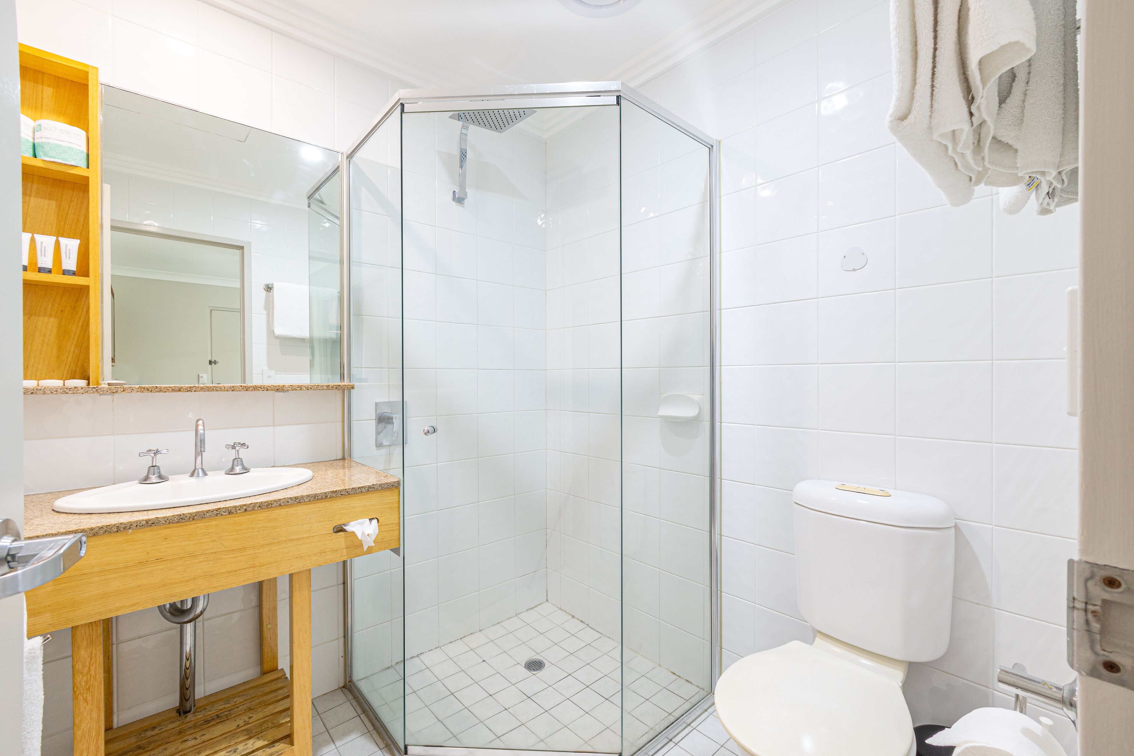 A modern bathroom with a glass-enclosed shower, a wooden vanity with a sink, and a toilet.
