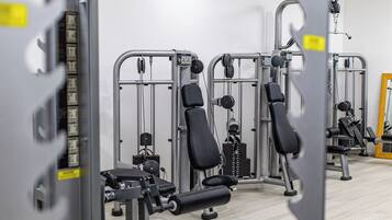 A gym with various exercise machines and benches.