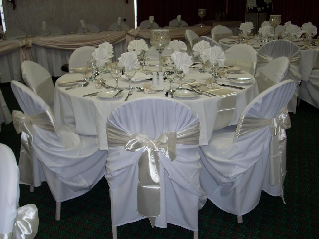 A banquet hall with round tables set for a formal event, each with white tablecloths and silverware.