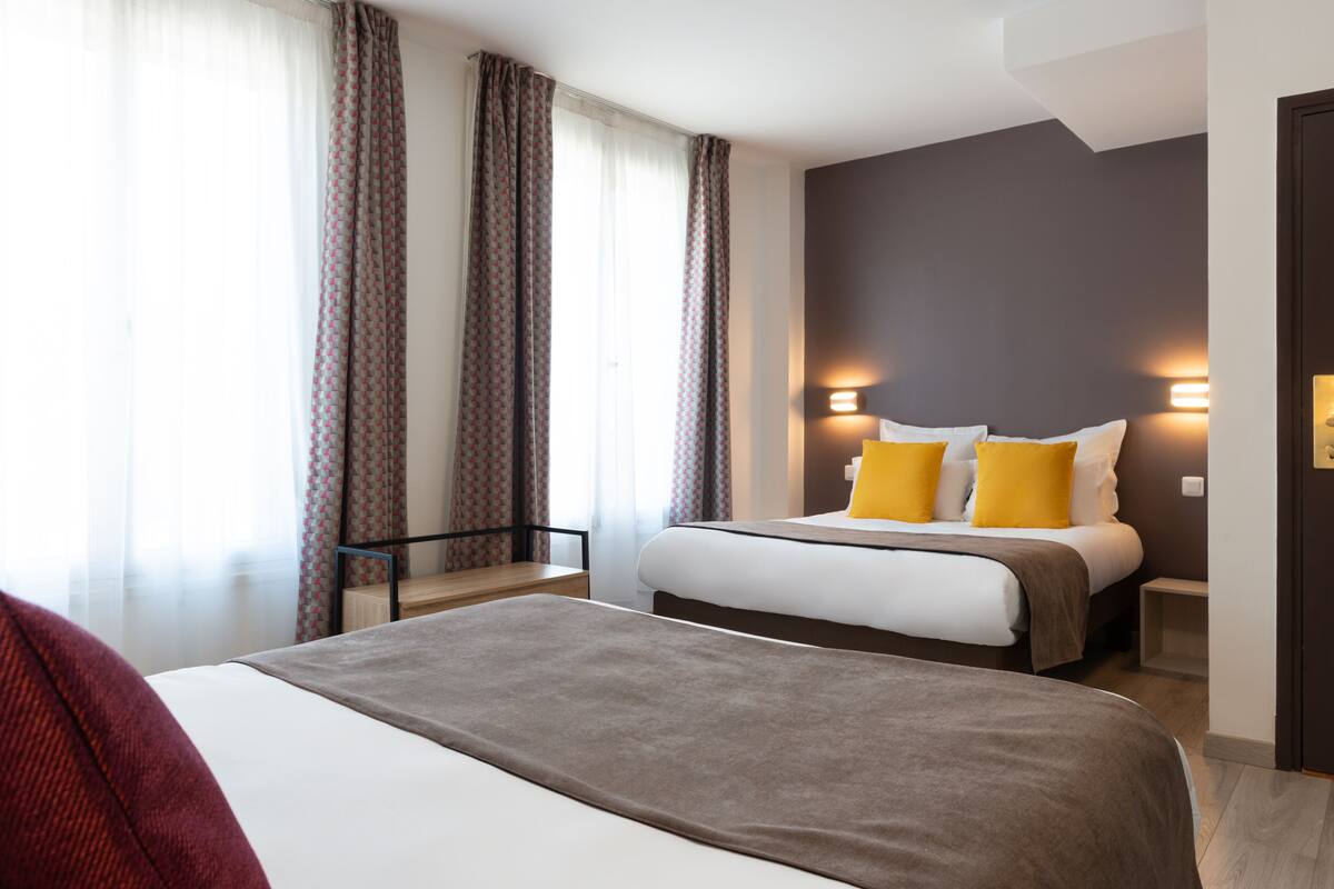 Une chambre d’hôtel avec deux lits, un bureau et une chaise.