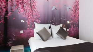 Een slaapkamer met een bed, kussens, een nachtkastje en een muurschildering van kersenbloesems en vogels.