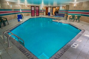 An indoor swimming pool with clear water, tiled walls, and a safety sign.