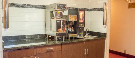 A kitchenette with a coffee machine, a coffee maker, and a chocolate dispenser.