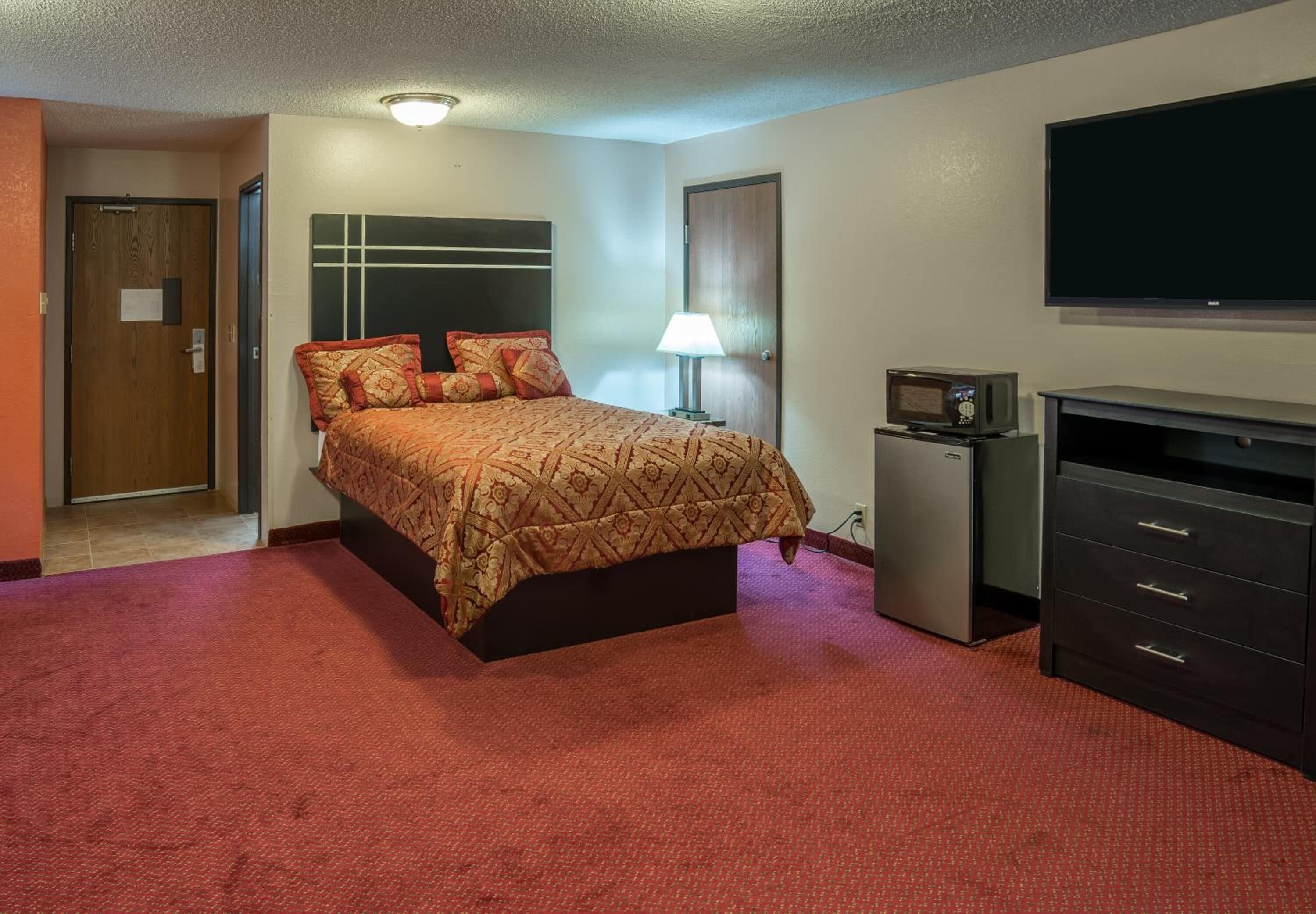 Une chambre d’hôtel avec un lit, une télévision, un bureau et une lampe.