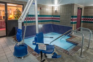 A pool area with a lift chair, a pool lift, and a tiled wall with a geometric pattern.