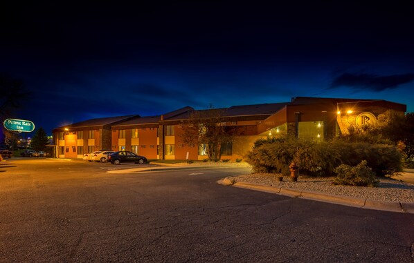 A motel with a parking lot, a sign indicating a Prime Rate Inn, and a well-lit building facade.