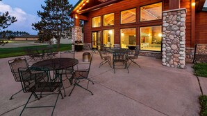 Un bâtiment en bois doté de grandes fenêtres, d’une terrasse et de piliers en pierre.