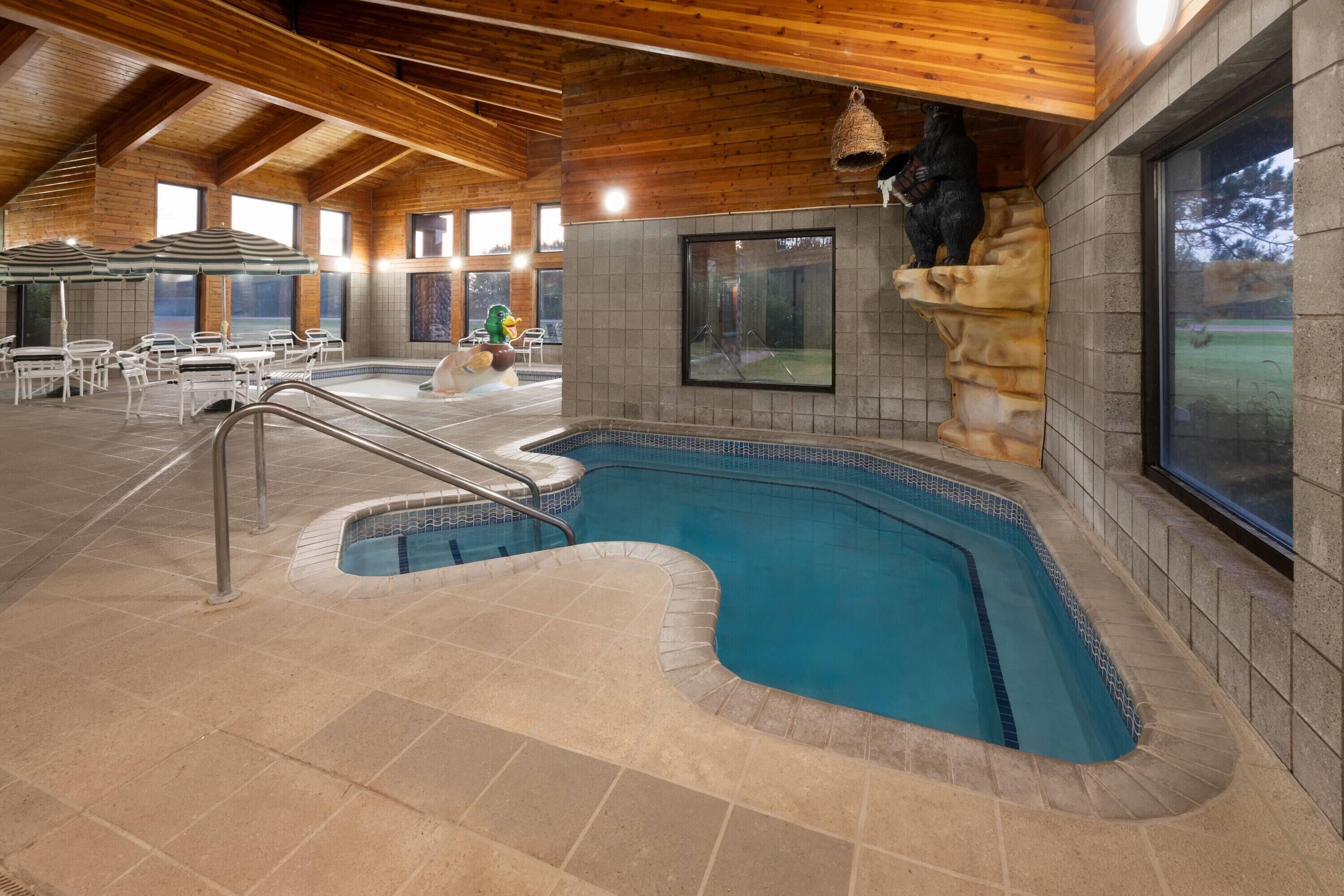 Una piscina interior con pared de piedra y techo de madera.
