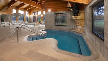 Una piscina interior con pared de piedra y techo de madera.