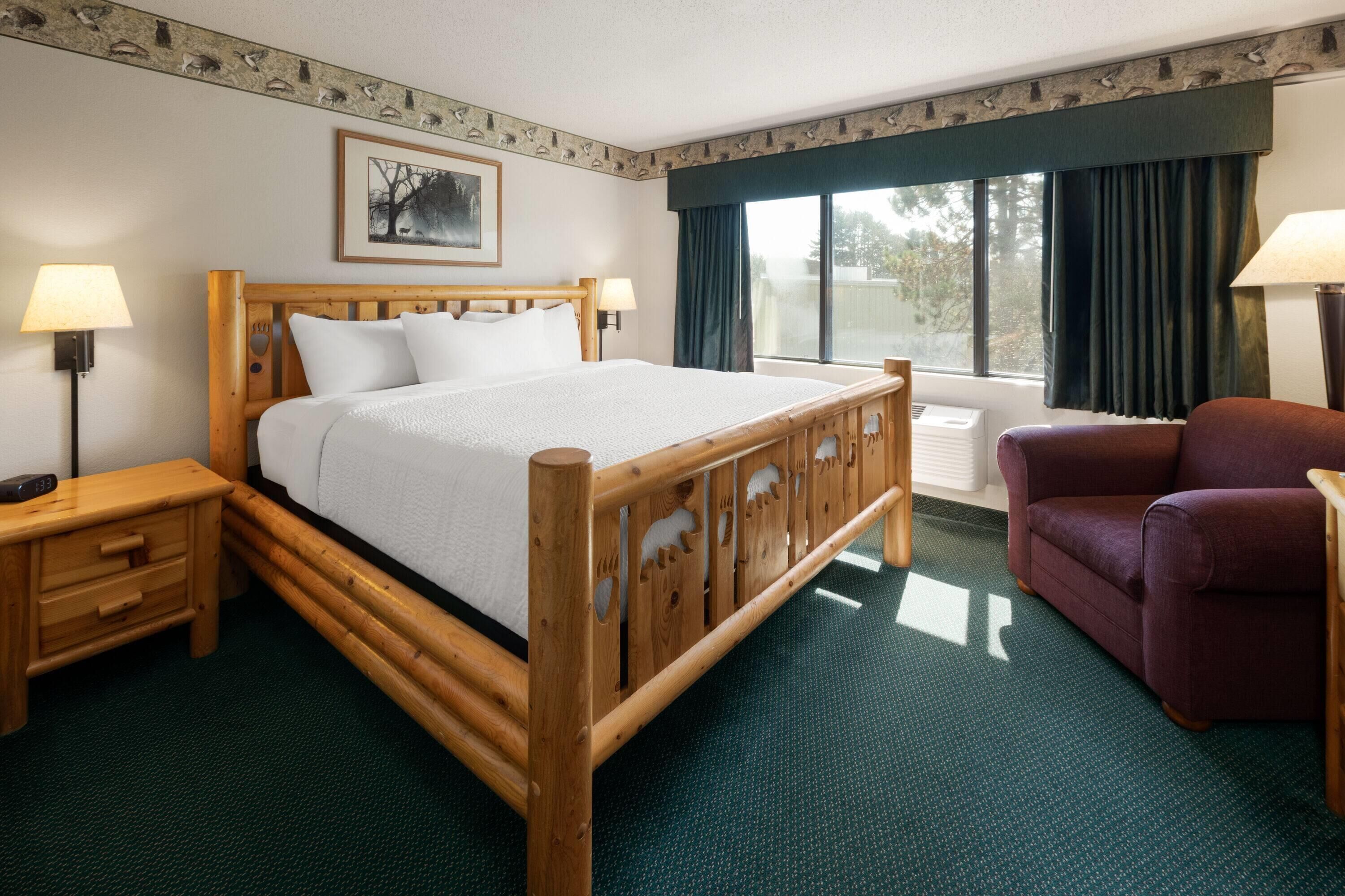 A hotel room with a wooden bed, a nightstand, a chair, and a window with curtains.