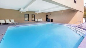 Ein Schwimmbad mit Liegestühlen und einer überdachten Liegefläche.