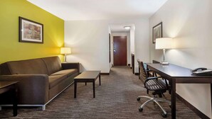 Ein Hotelzimmer mit einem braunen Sofa, einem kleinen Tisch, einem Schreibtisch mit Stuhl und einer Lampe.