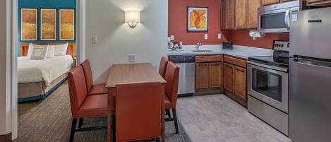 A modern kitchen with stainless steel appliances, wooden cabinets, and a dining area with a table and chairs.
