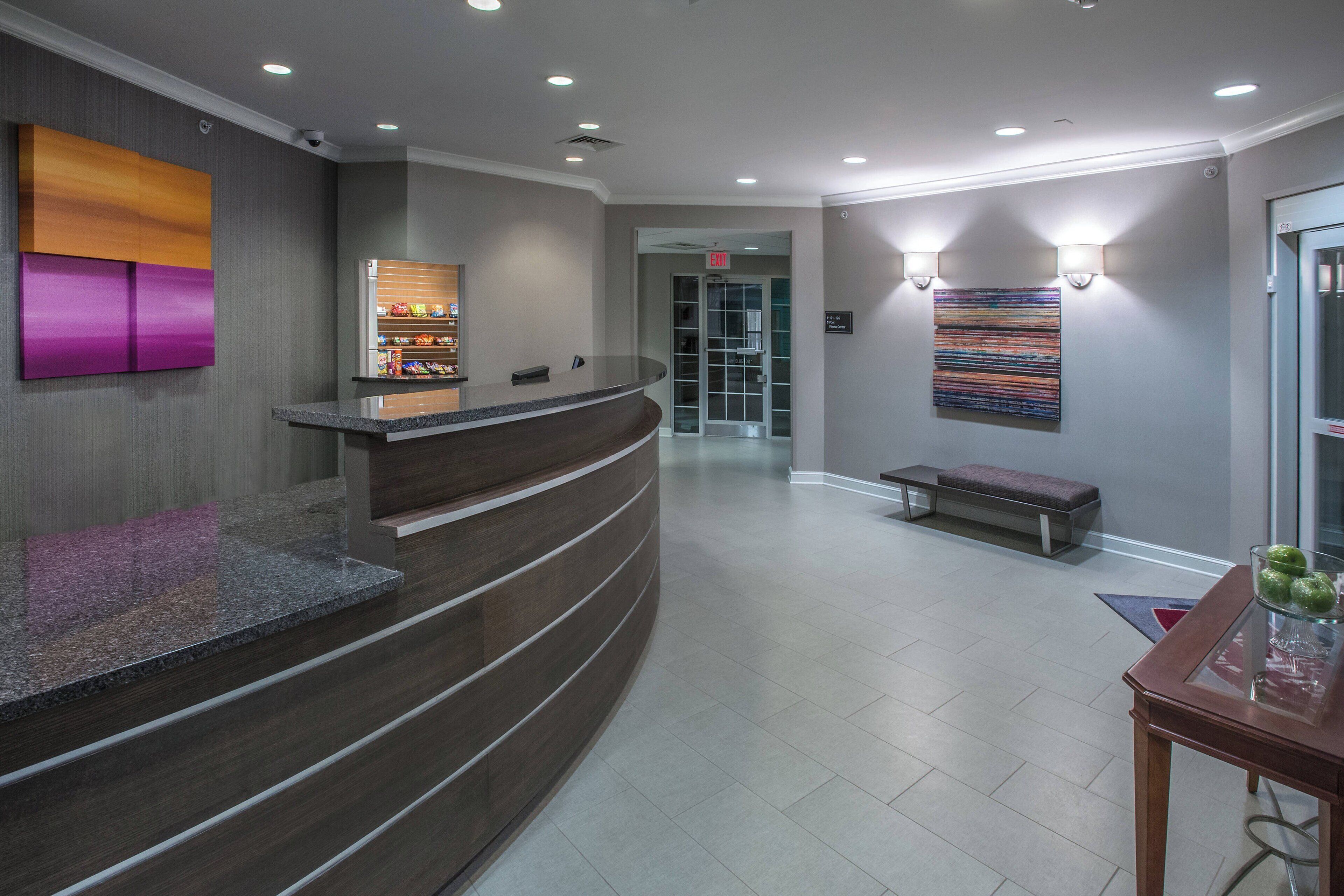A reception area with a curved counter, a bench, and a wall-mounted light fixture.