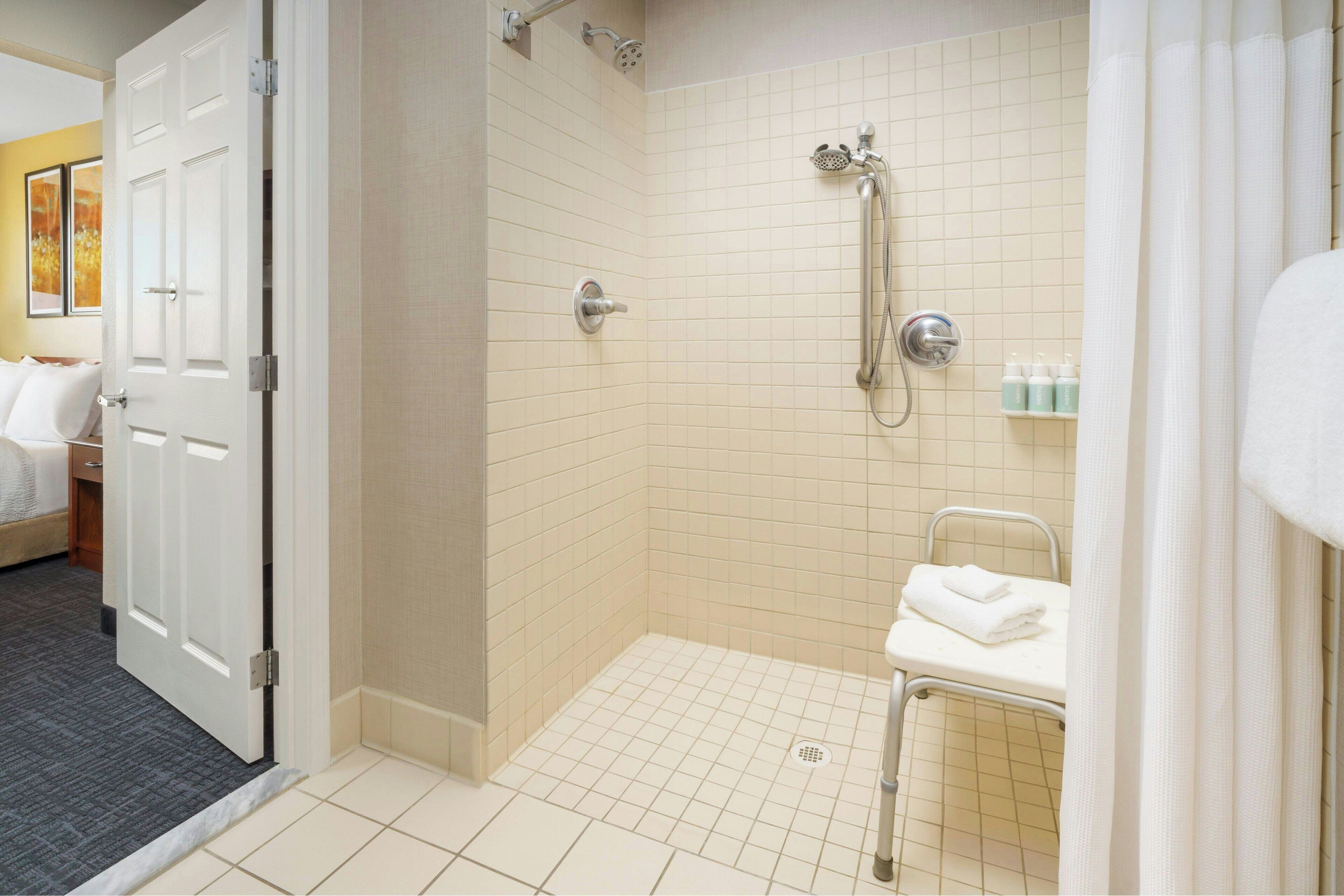 A hotel bathroom with a shower, a sink, and a towel rack.
