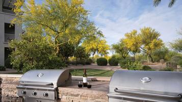 Deux barbecues en acier inoxydable, une bouteille de vin et deux verres, le tout sur une terrasse.