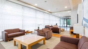 A spacious lobby with a large seating area, a wooden table, and a modern interior design.