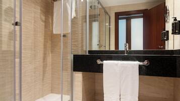 A modern bathroom with a glass shower enclosure, a black countertop sink, and a white towel hanging on a metal rack.
