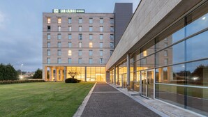 Ein modernes Hotel mit einem markanten Eingang, großen Glasfenstern und einem gepflegten Rasen.