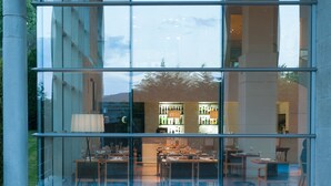 Ein Restaurant mit Glasfassade, Tischen, Stühlen und einem sichtbaren Barbereich durch die Fenster.