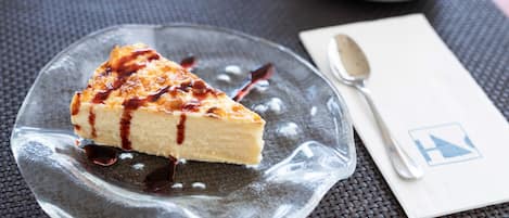 A slice of cheesecake on a clear glass plate with a spoon and napkin on a table.