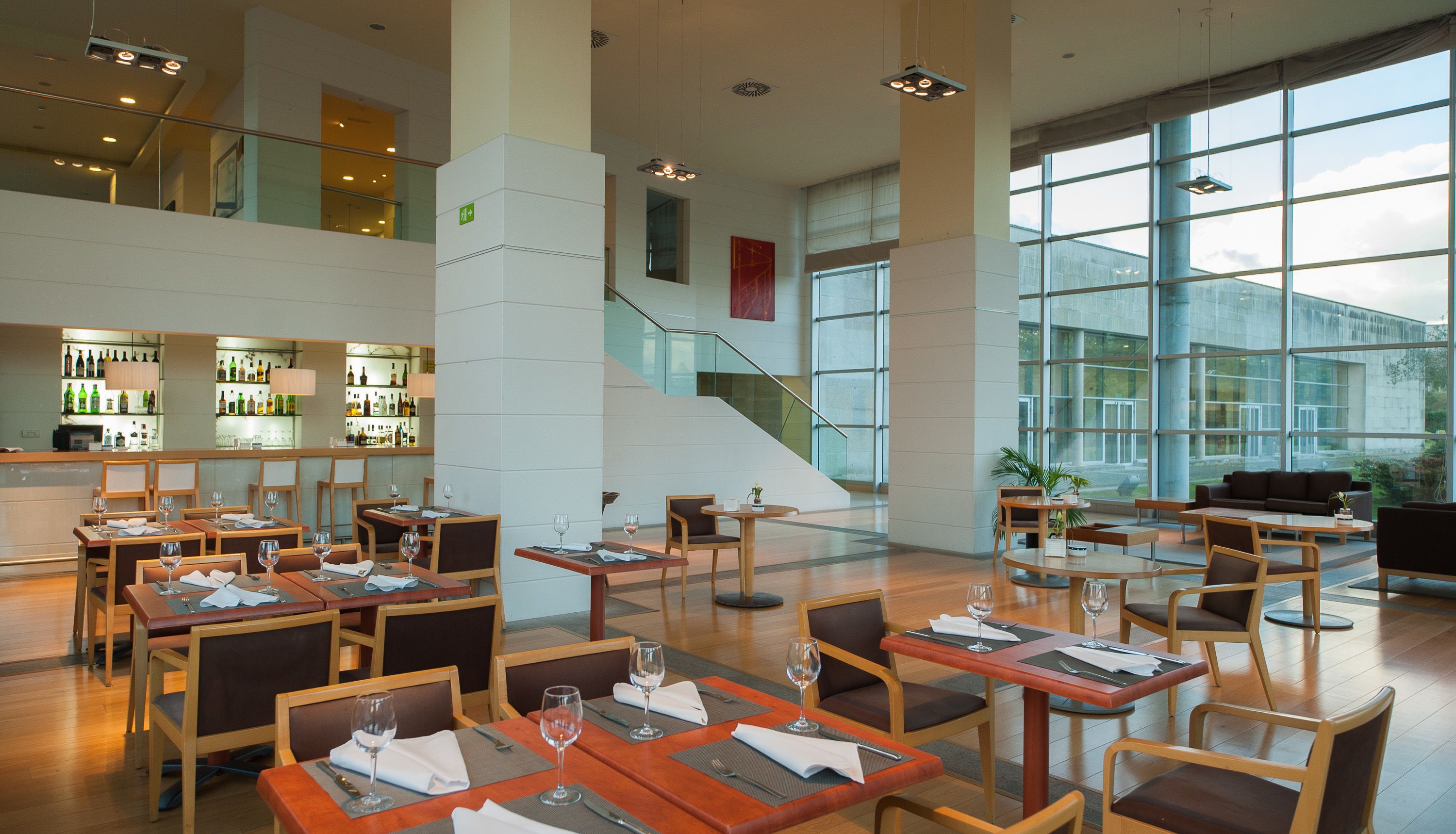 En modern restaurang med flera olika matplatser, en bar och stora fönster som ger utsikt över omgivningarna.