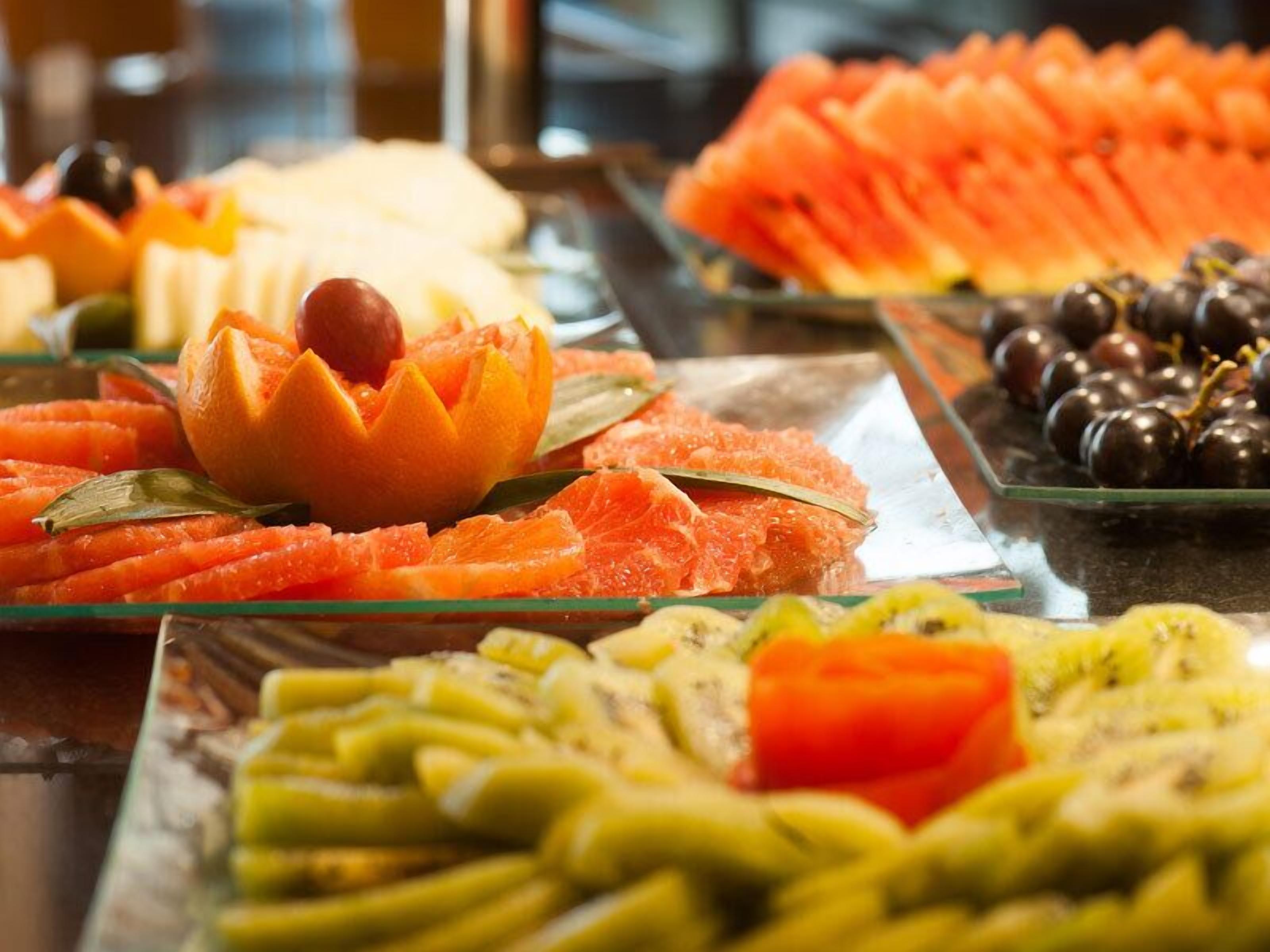 Ein Buffet mit verschiedenen Früchten und Gemüsesorten, darunter Orangenscheiben, Karotten und Trauben.
