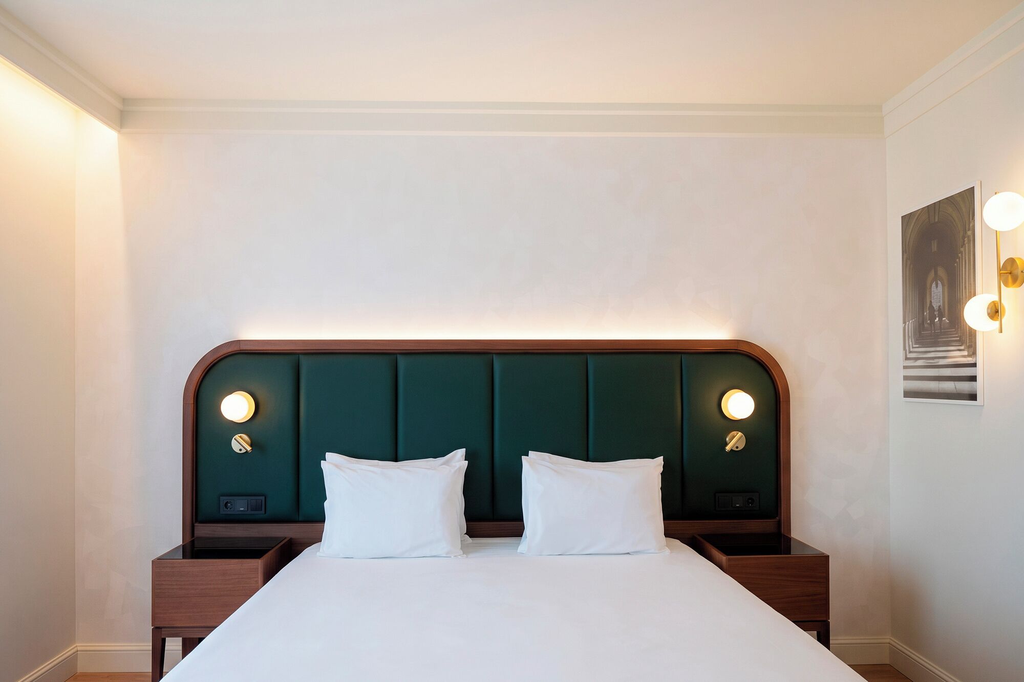 Ein Hotelzimmer mit einem großen Bett, zwei Nachttischen und einem Kopfteil mit integrierter Beleuchtung.