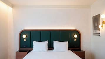 Una habitación de hotel con una cama grande, dos mesitas de noche y un cabecero con iluminación integrada.