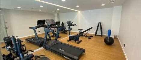 Un gimnasio en casa con cintas de correr, elípticas y pelotas de ejercicio.