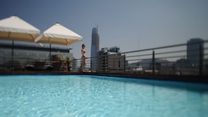 A swimming pool with a cityscape in the background. - Time Suite - Comfort Apartments (Santiago)