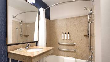 A bathroom with a sink, mirror, shower, and bathtub.