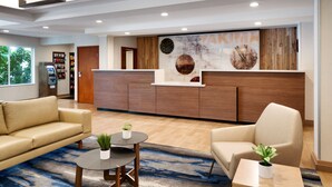 A reception area with a wooden reception desk, a beige sofa, and a coffee table with a plant. - Fairfield Inn and Suites by Marriott Yakima (Yakima)