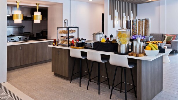 A modern kitchen with a central island, bar stools, and a breakfast bar. - Hilton Garden Inn Birmingham/Lakeshore Drive (Birmingham)