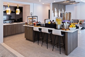 Una cocina moderna con una isla central, taburetes de bar y una barra para desayunos.