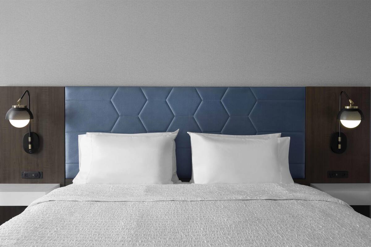 A bed with a headboard, two bedside lamps, and a white bedspread.