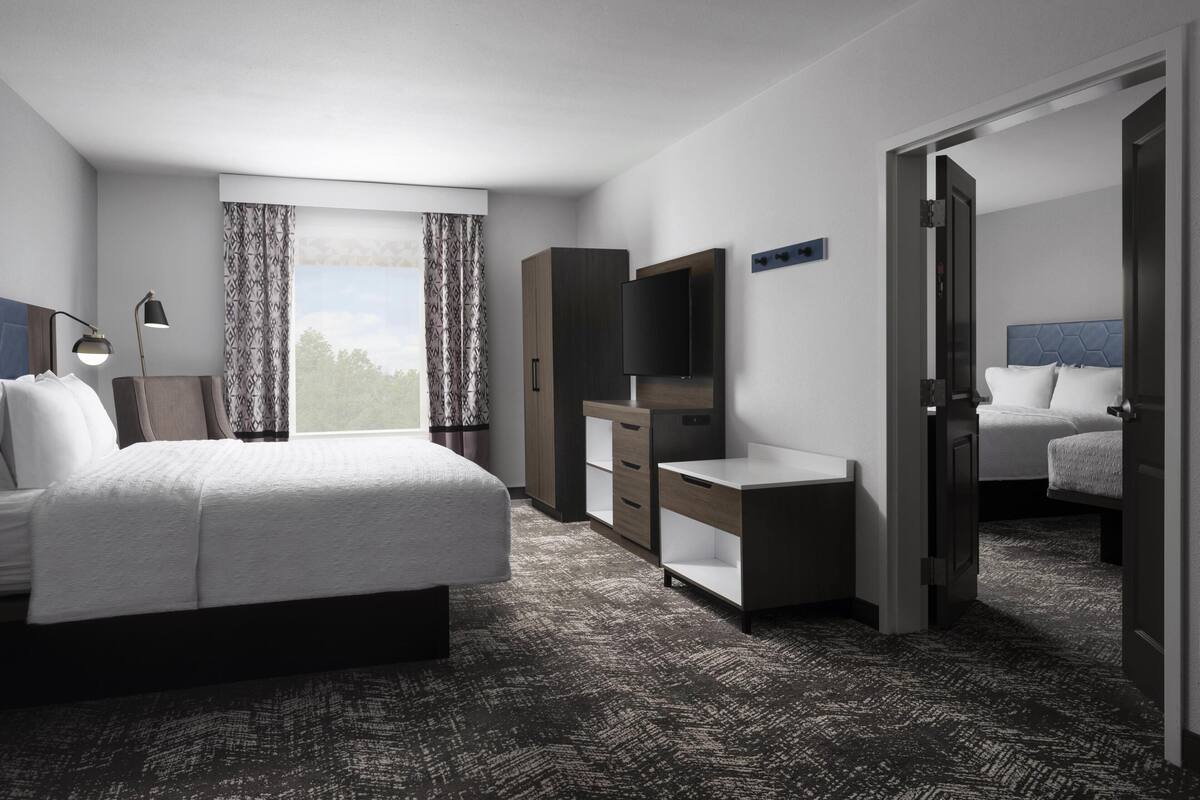 A hotel room with a bed, a desk, a TV, and a wardrobe.