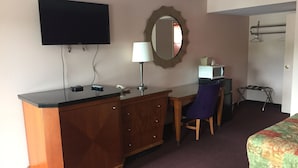 A hotel room with a wooden desk, a television, a mirror, a bed, and a small table with a microwave. - Scottish Inns Albany (Albany)