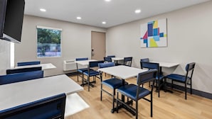 A modern dining area with tables and chairs, a large window, and a geometric art piece on the wall. - Park Inn by Radisson, Salt Lake City Downtown (Salt Lake City)