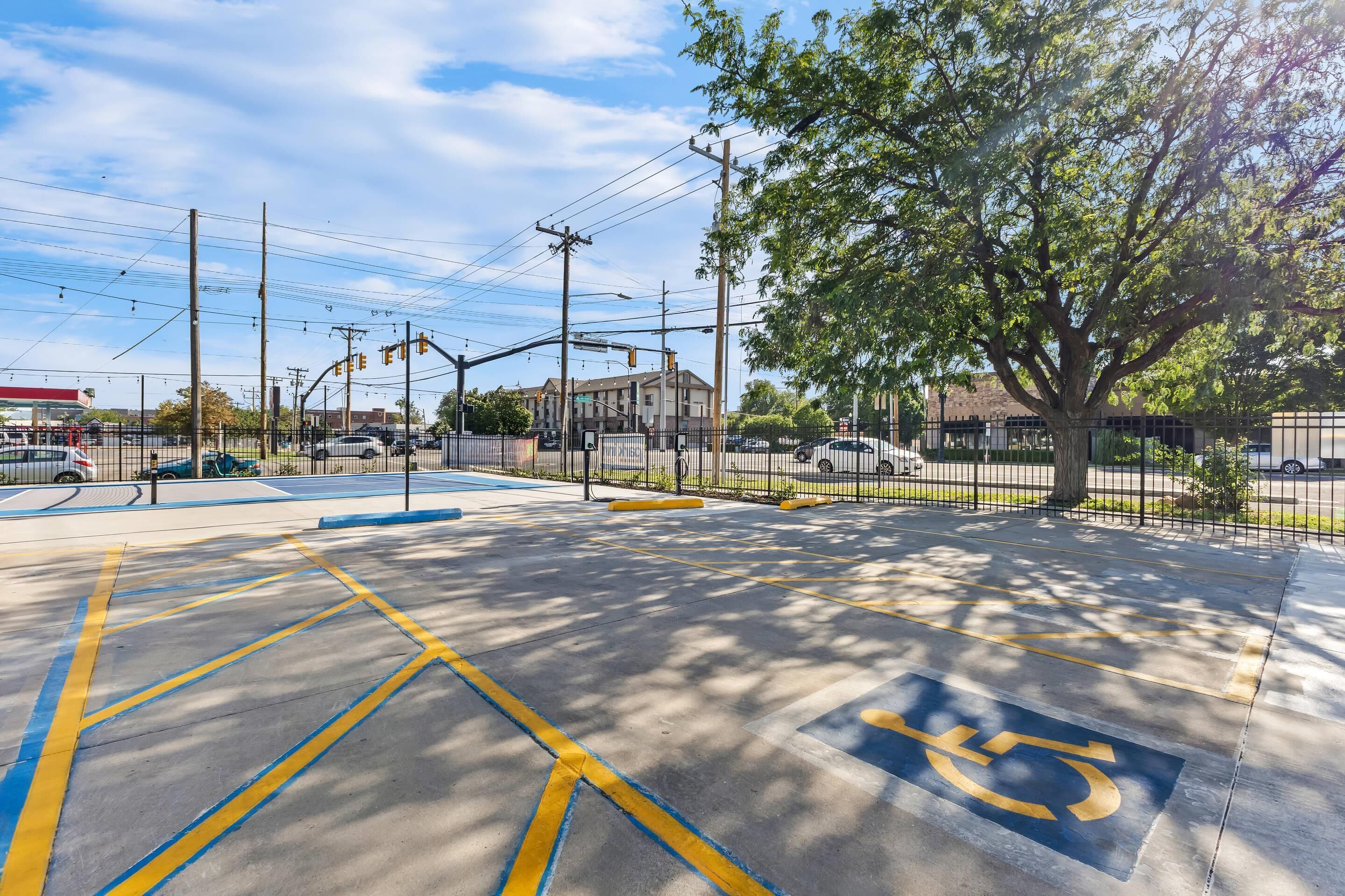 A parking lot with marked handicapped spaces, a gas station, and a building in the background.